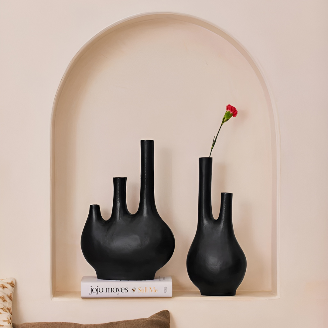 Two matte black double neck vases, handcrafted with an aged metal finish, add modern elegance to home decor.