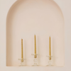 Set of three gold twisted taper candles on glass candle holders, creating a warm, elegant ambiance.