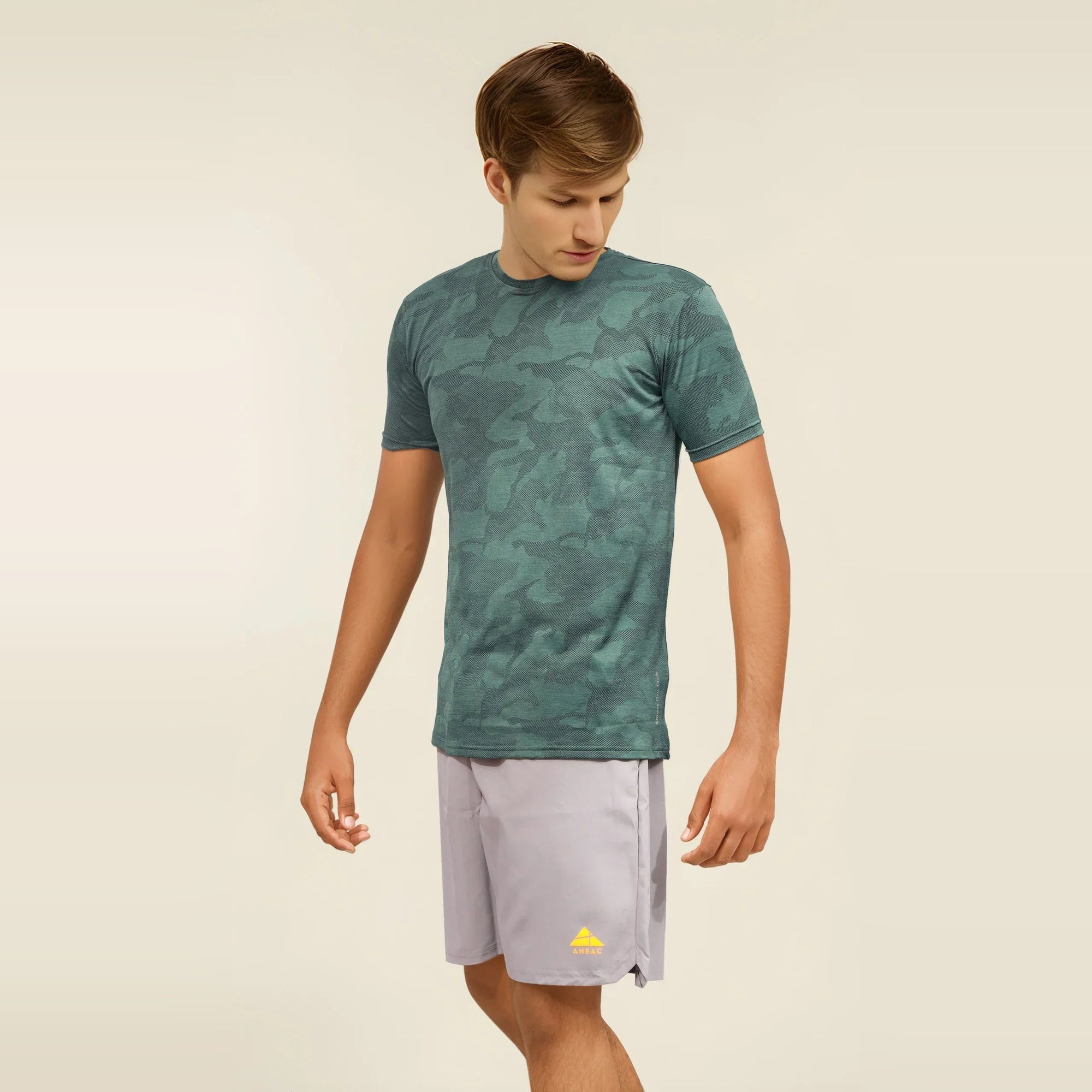 Man wearing a green camouflage, dry-fit, crew neck t-shirt ideal for workouts and staying cool.