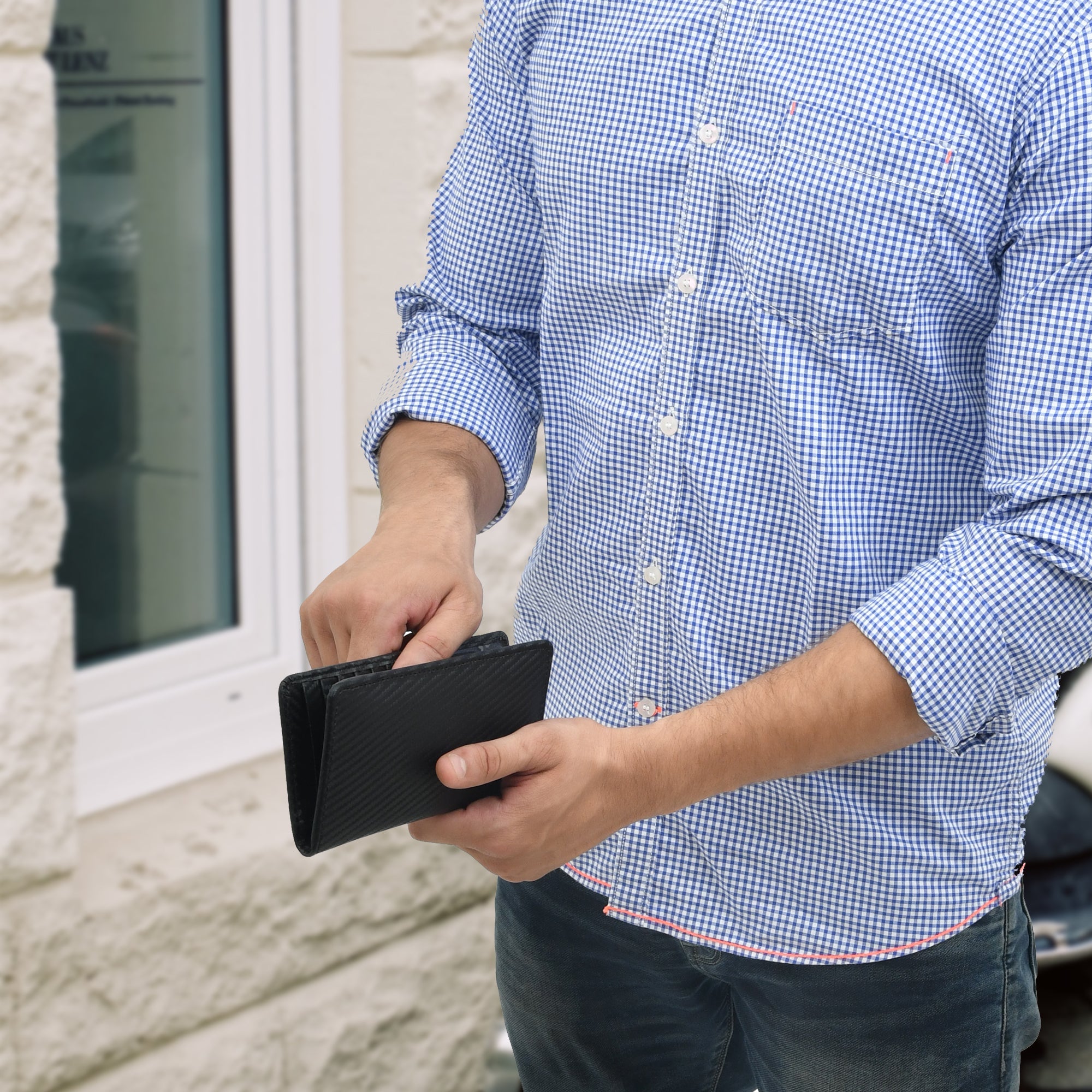 Man holding a black leather RFID blocking minimalist bifold long wallet.