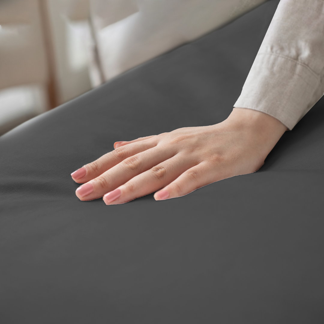 Hand feeling the softness of a grey 100% Egyptian cotton queen size bed sheet with 300 thread count.