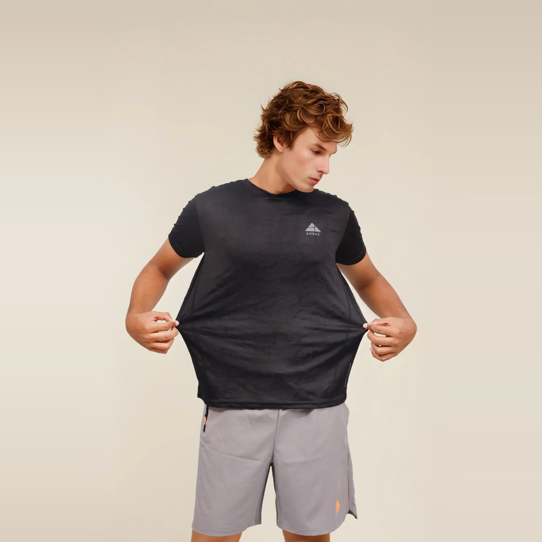 Man demonstrating the breathable, dry-fit fabric of a black crew neck workout t-shirt.