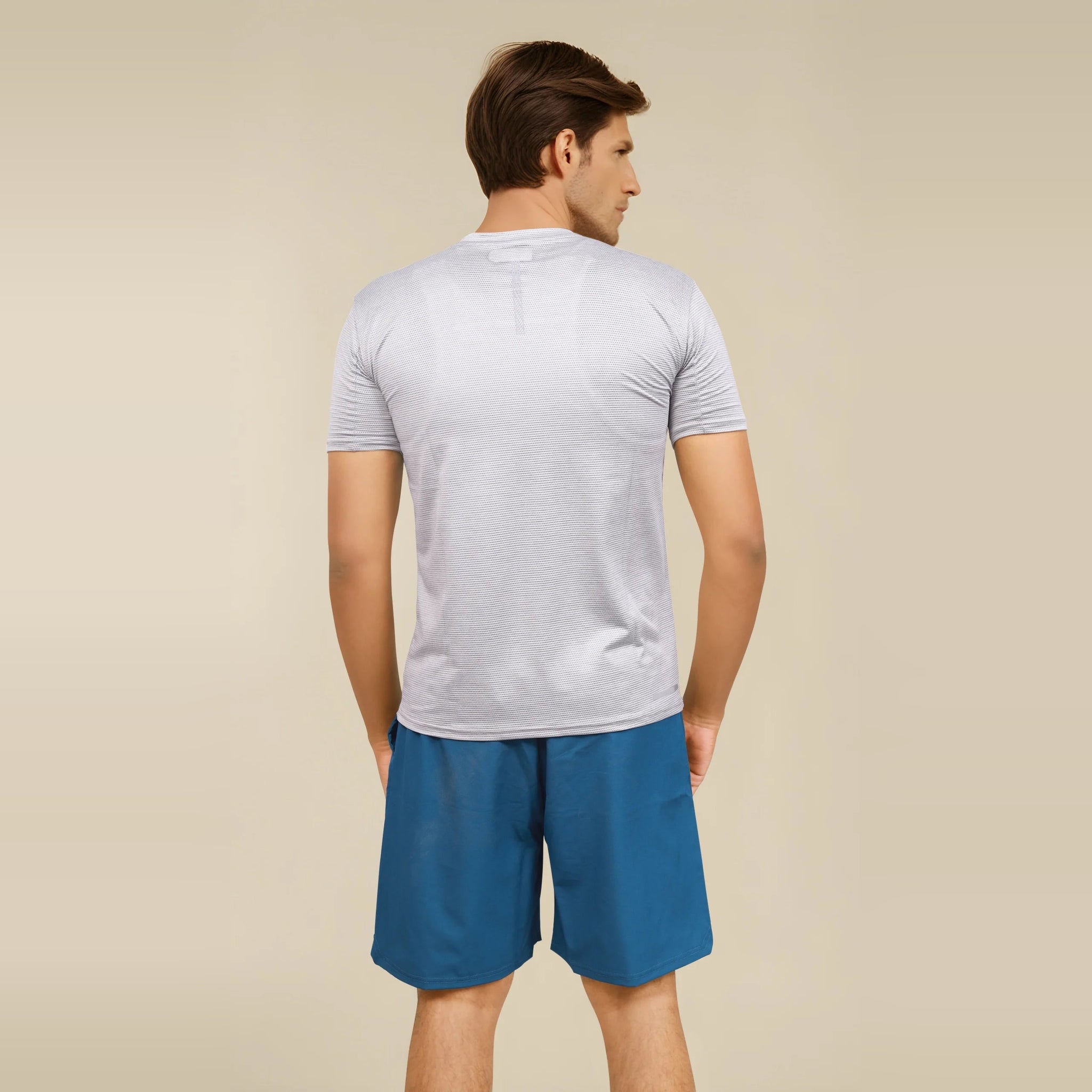 Man wearing a slim-fit, short sleeve, gray t-shirt, showcasing its fit and style from the back.