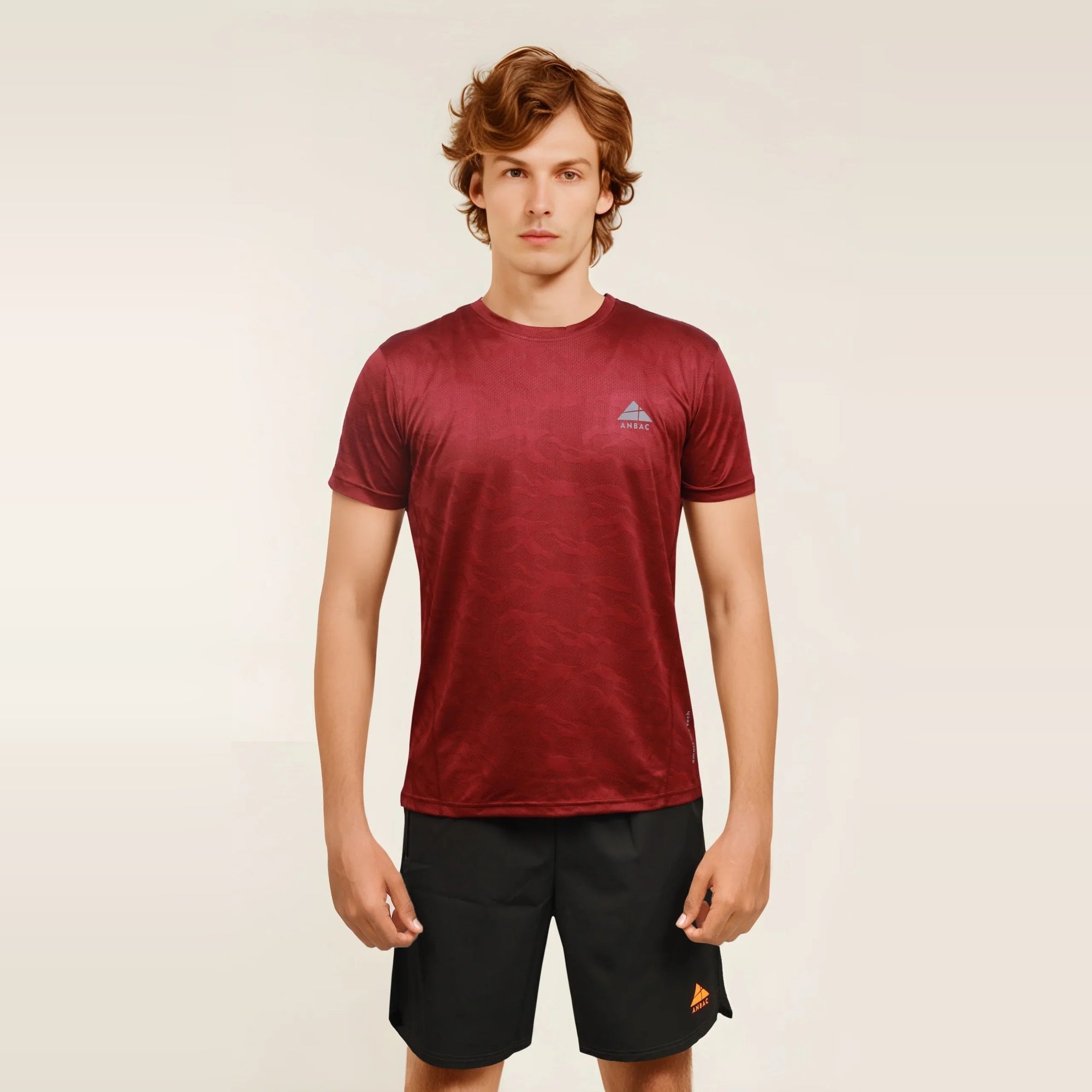 Man wearing a maroon dry-fit crew neck t-shirt designed for workouts and active wear.