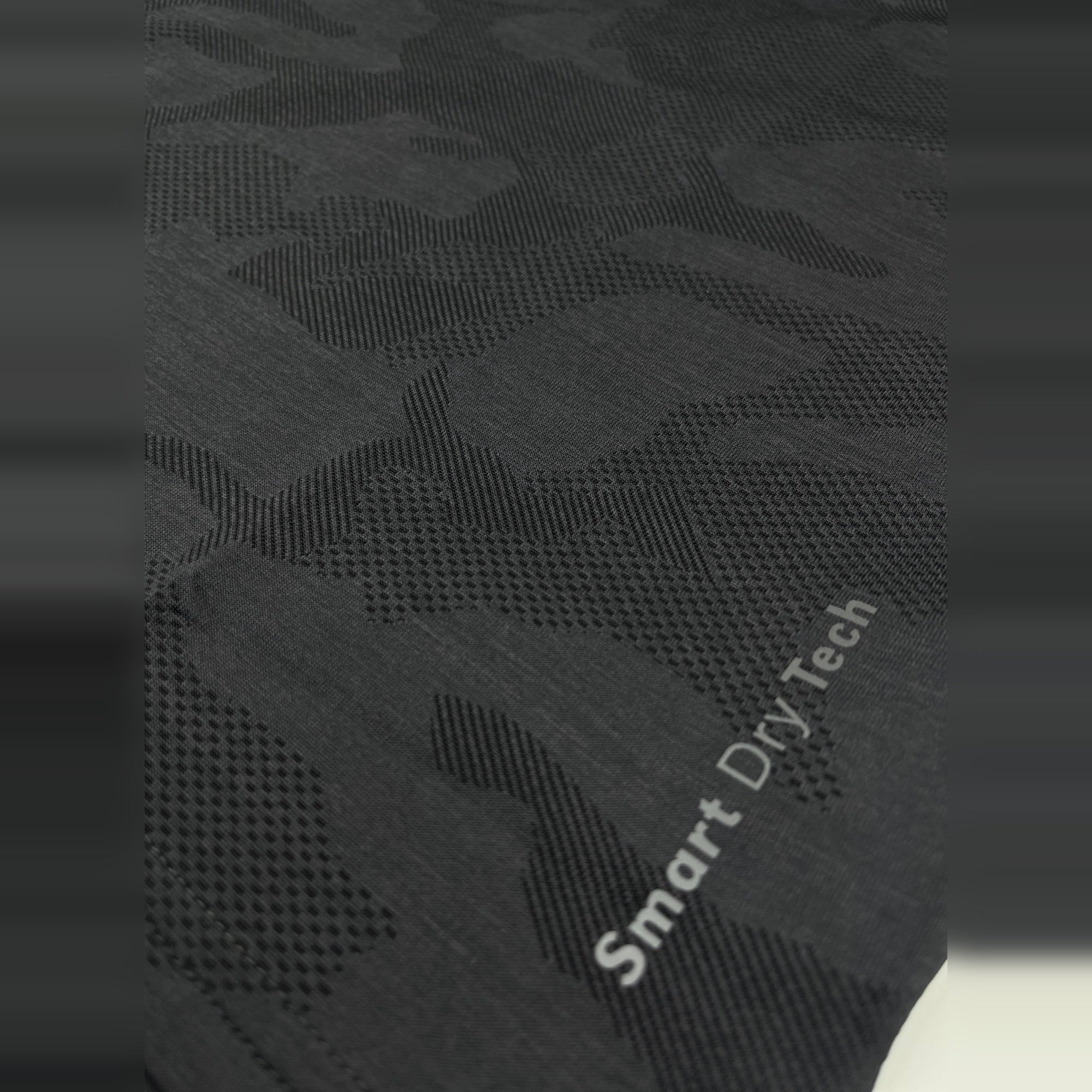 Close-up of black, breathable men's workout T-shirt fabric with "Smart Dry Tech" woven into the design.