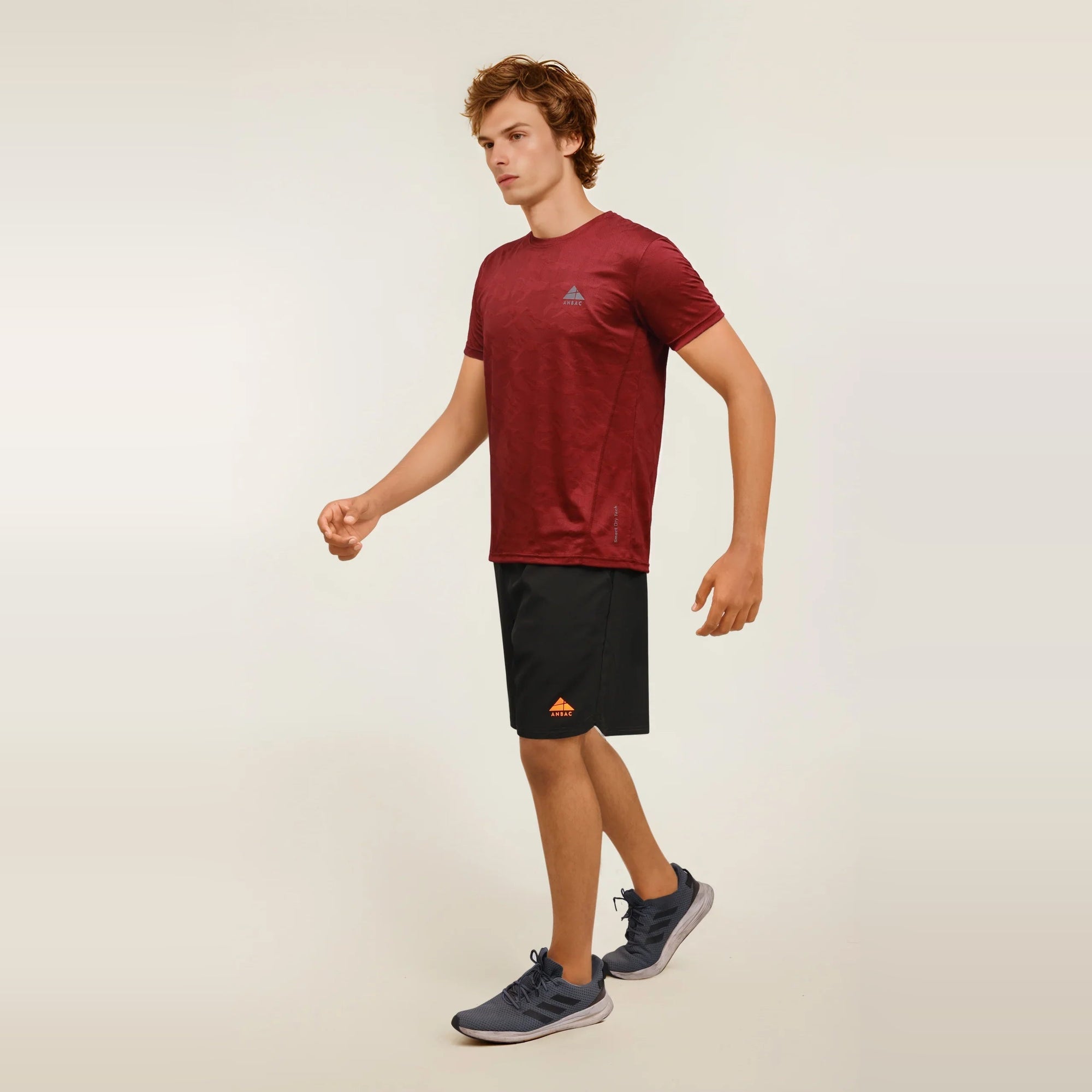 A man walks in a blue, dry-fit, crew neck t-shirt, ideal for workouts and athletic activities.