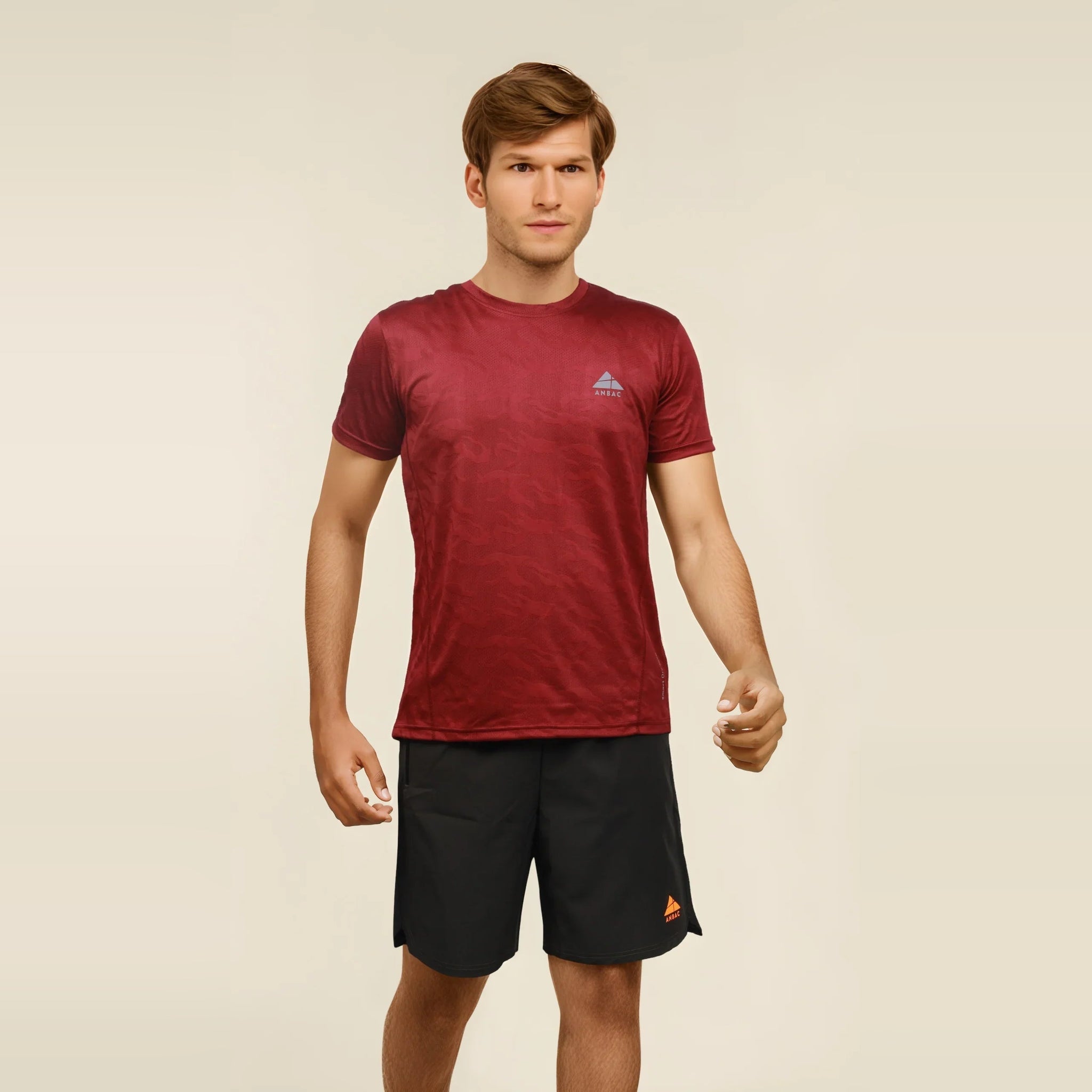 Man in maroon dry-fit workout t-shirt. Breathable, crew neck tee ideal for workouts and athletic activity.