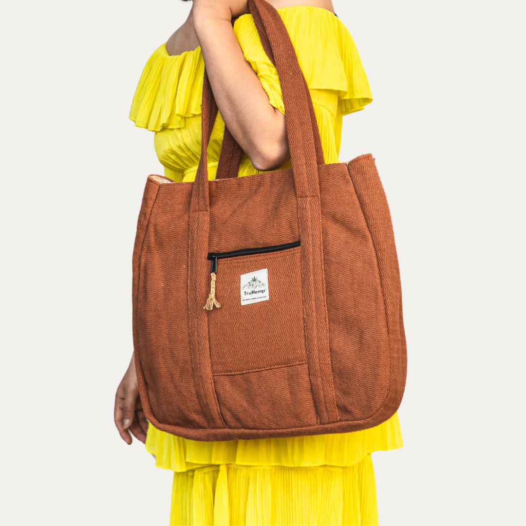 A woman models a spacious, rust-colored Himalayan Hemp Tote Shoulder Bag with a front pocket, perfect for eco-conscious individuals.