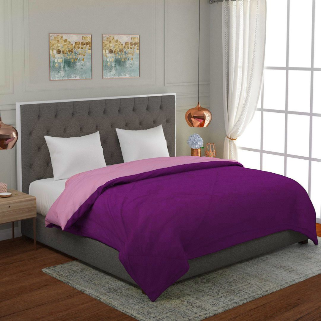 A plush, purple Bellolin microfiber comforter draped over a double bed. This reversible comforter is lightweight and breathable, perfect for year-round comfort.