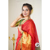 A woman smiles in a red and green Banarasi silk saree with gold printed details, showcasing its elegance and drape.