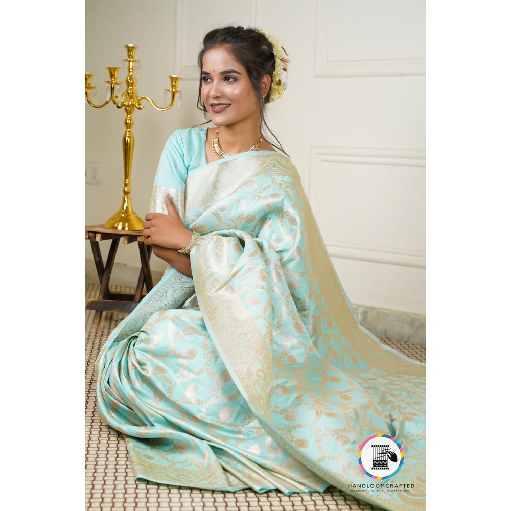 A woman gracefully wears a sky blue Banarasi tissue silk saree with intricate gold floral prints, showcasing its elegant drape and luxurious feel.