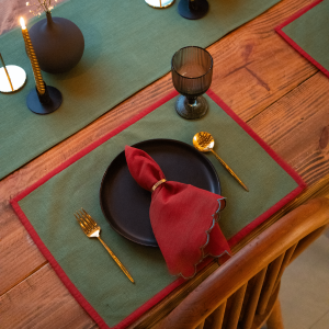 Green and red yarn-dyed cotton table runner on a wooden table set for a meal. The runner is 14x92 inches.