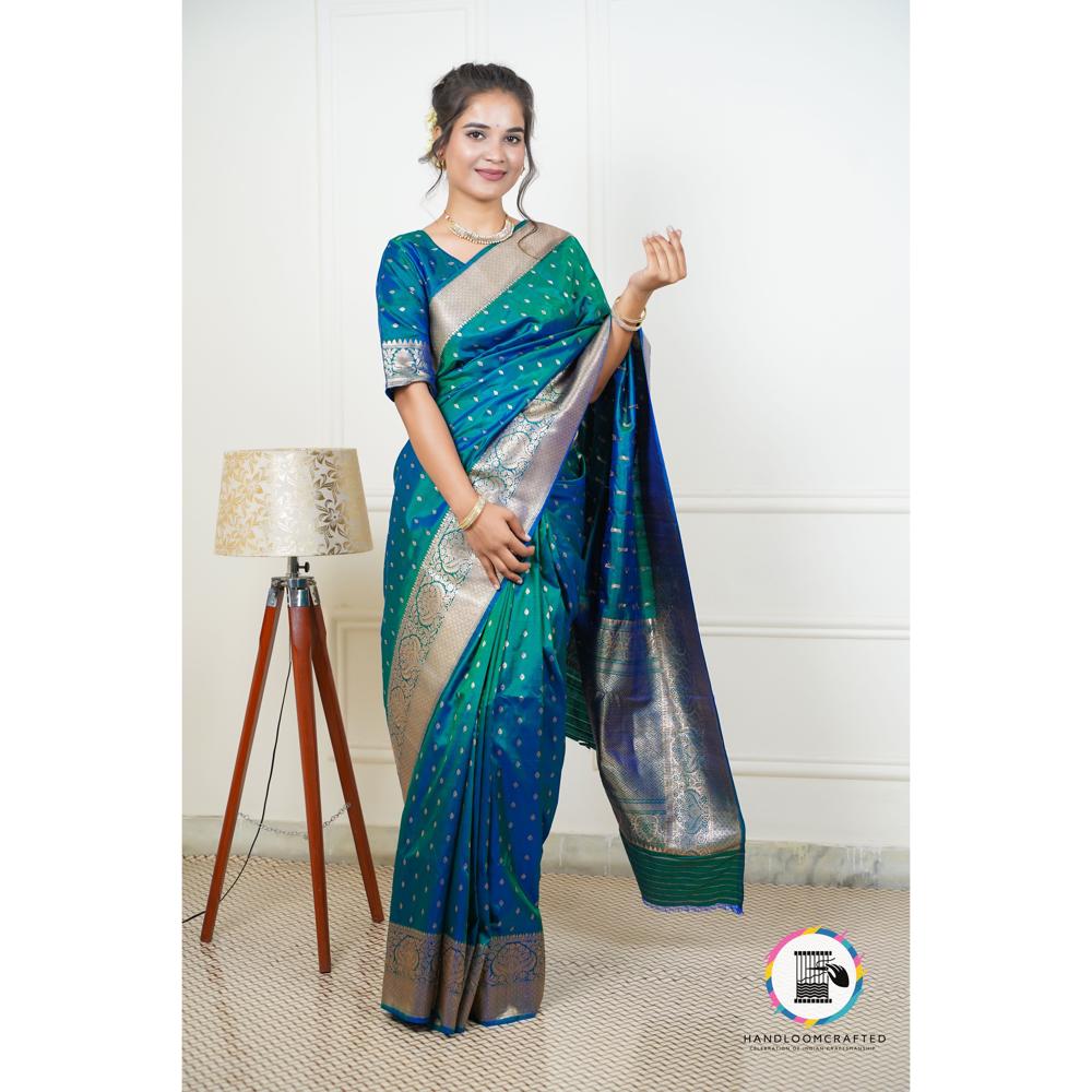 A woman modeling a vibrant blue Banarasi silk saree with a printed pattern, showcasing its drape and intricate design details.