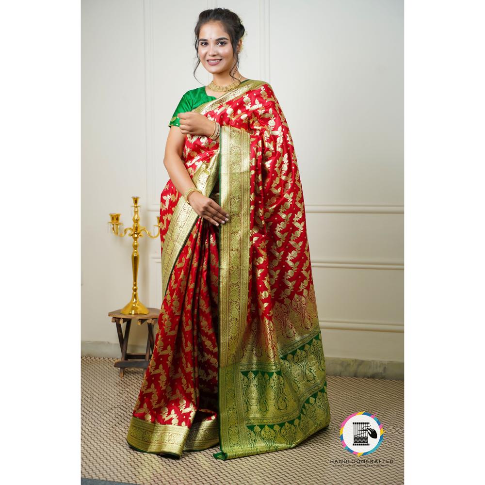 A model poses in a red and green Banarasi tissue silk saree with intricate gold prints, showcasing its vibrant color and luxurious drape.