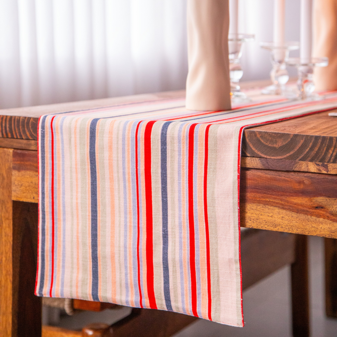 French Stripe Cotton Table Runner (14x82 inches) draped over a wooden table. The runner features red, blue, and cream stripes.