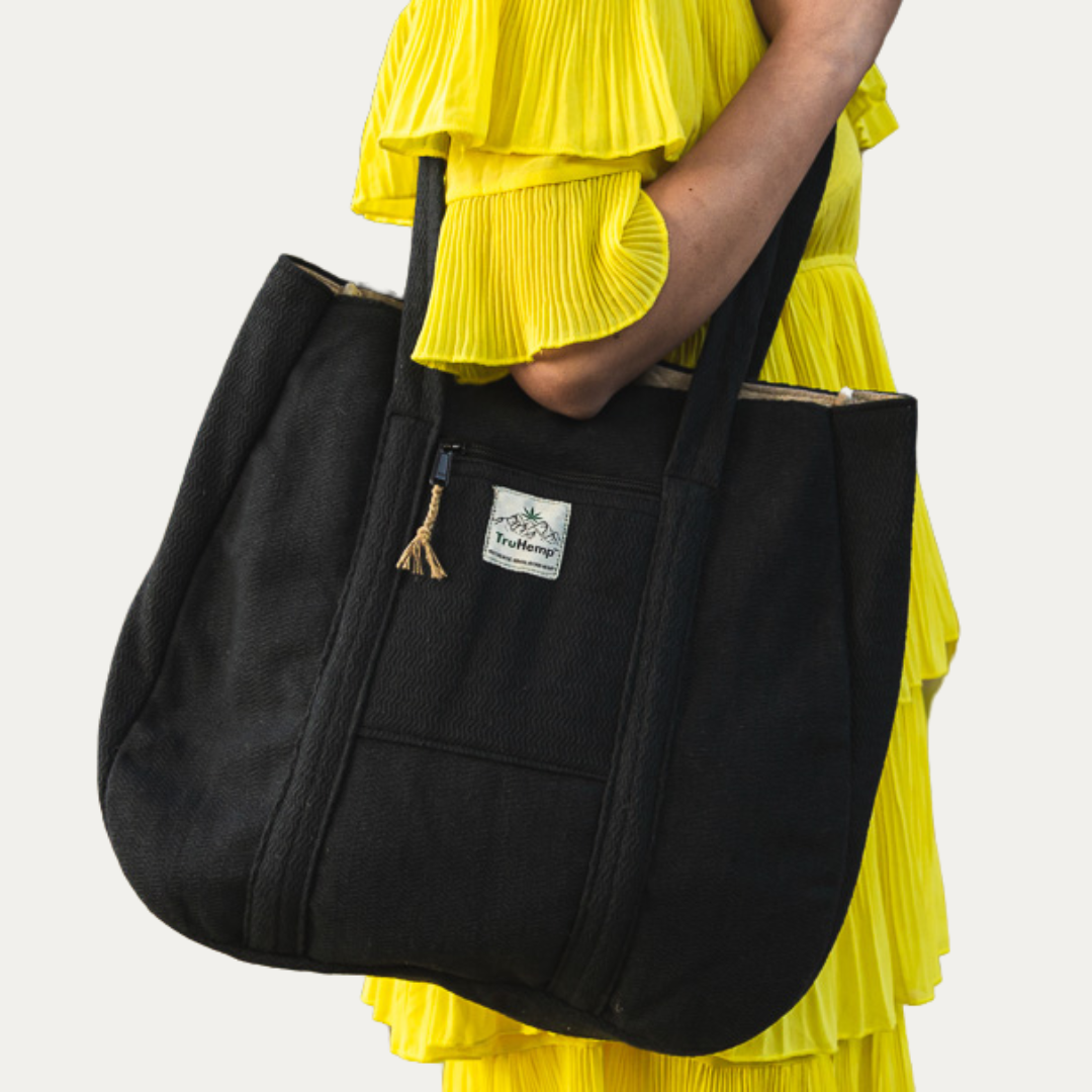 Black Himalayan Hemp Tote Shoulder Bag held by a woman in a yellow dress. This spacious and eco-friendly bag is perfect for everyday use.