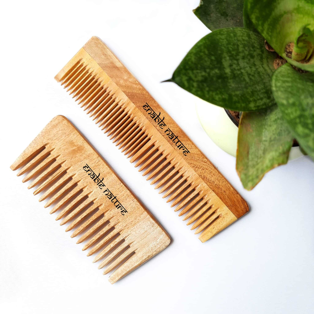 Two wooden hair combs made by Enable Nature lay side-by-side on a white surface.