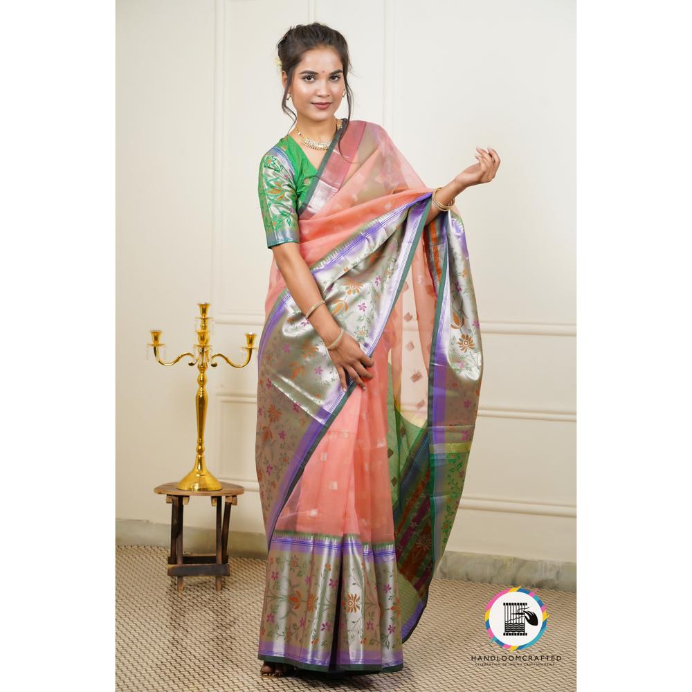 A woman poses in a peach-colored "Green Peach Printed Soft Banarasi Tissue Silk Saree" with intricate floral designs and a green and purple border.