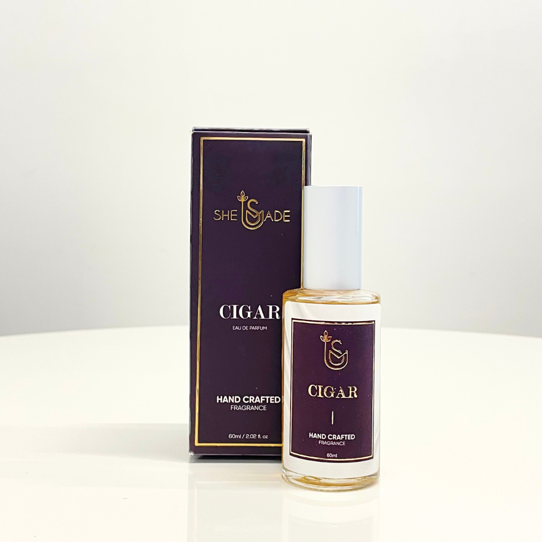 A bottle of SheMade Cigar perfume with packaging. This unisex fragrance has a rich, smoky scent and is long-lasting.