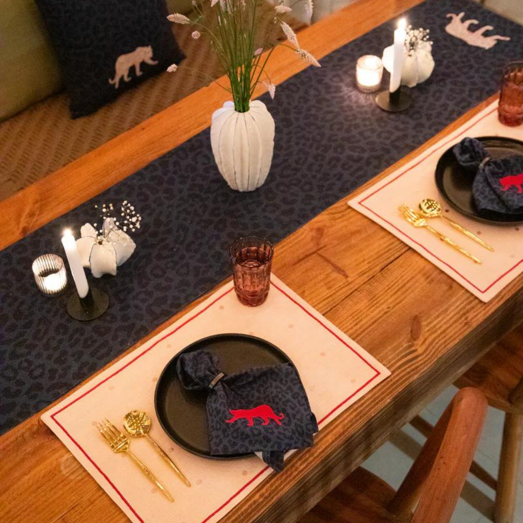 Navy blue cotton table runner with tiger embroidery, adding a touch of exotic style to a dining table setting.