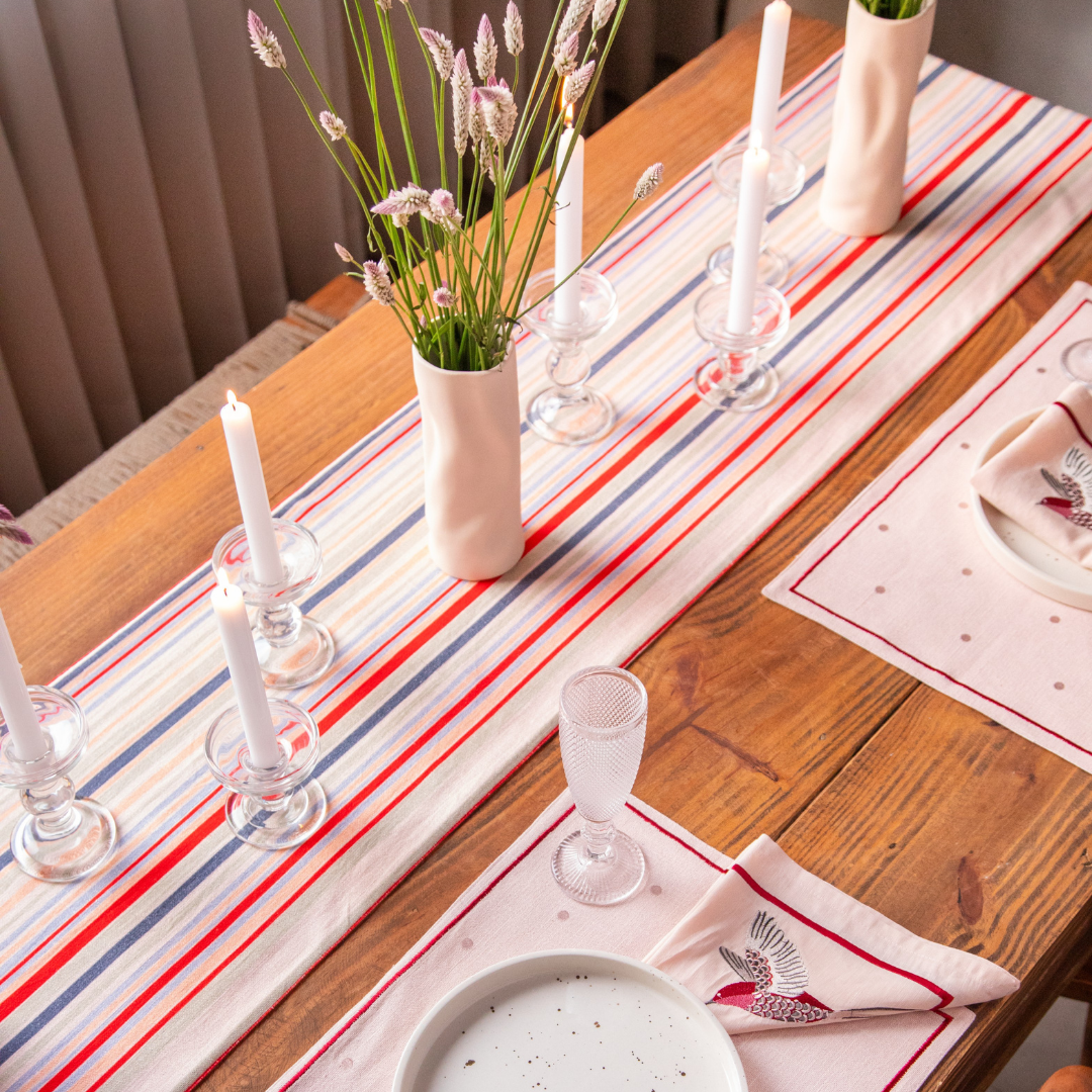 A colorful French stripe cotton table runner (14x82 inches) dresses up a table setting with candles and flowers.