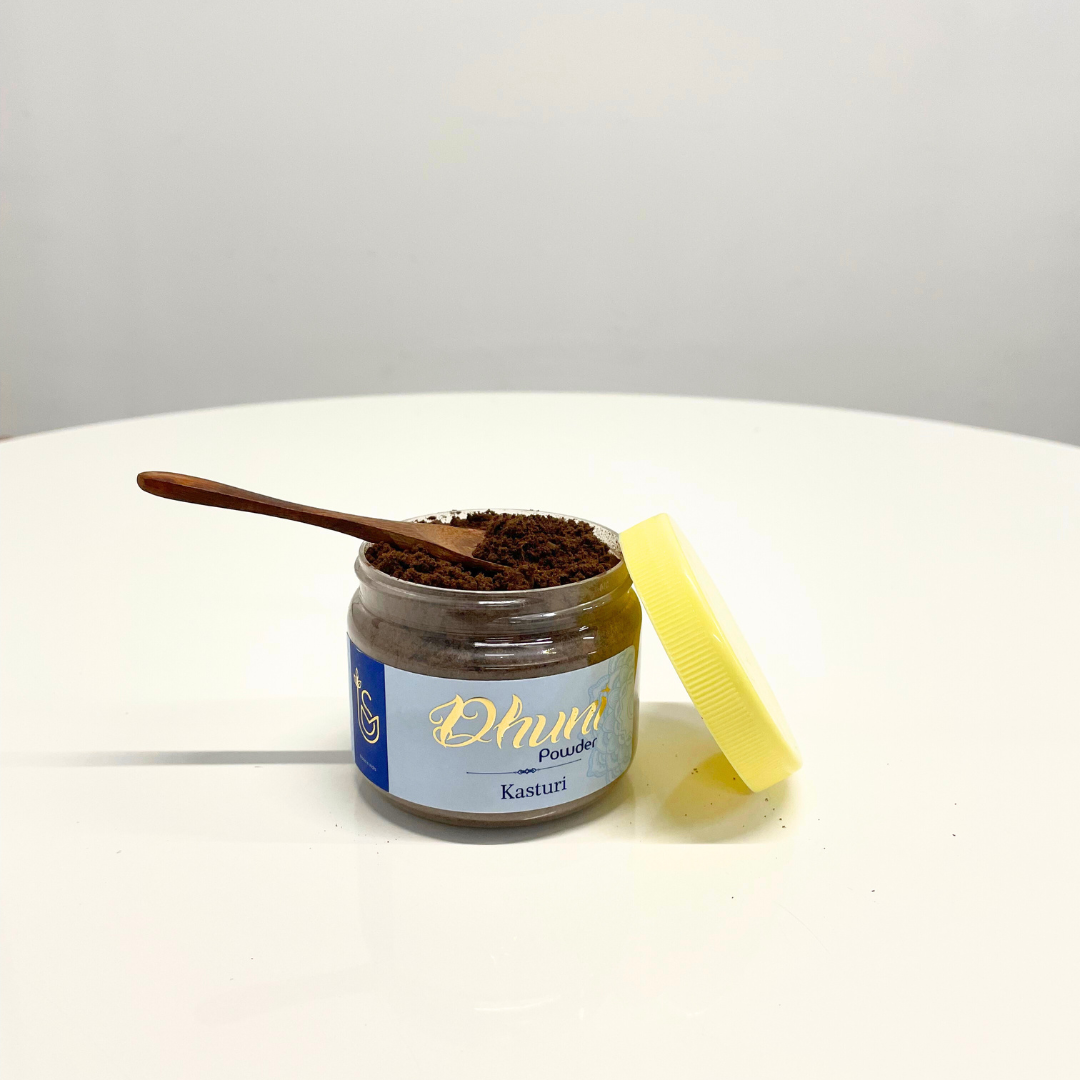 A jar of Kasturi Dhuni Powder with a wooden spoon, used for traditional Indian rituals and aromatherapy.