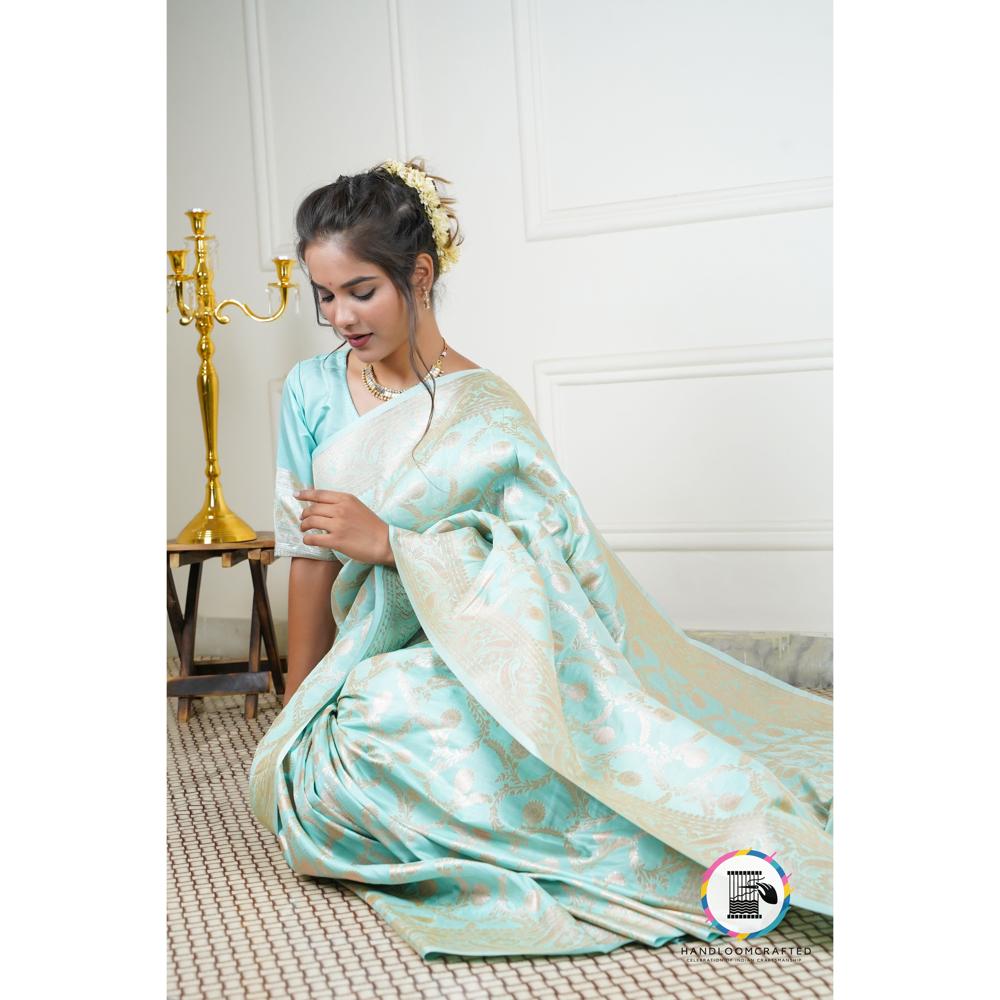 A woman gracefully wears a sky blue Banarasi silk saree with intricate gold floral patterns, showcasing the elegance and drape of this exquisite Indian garment.