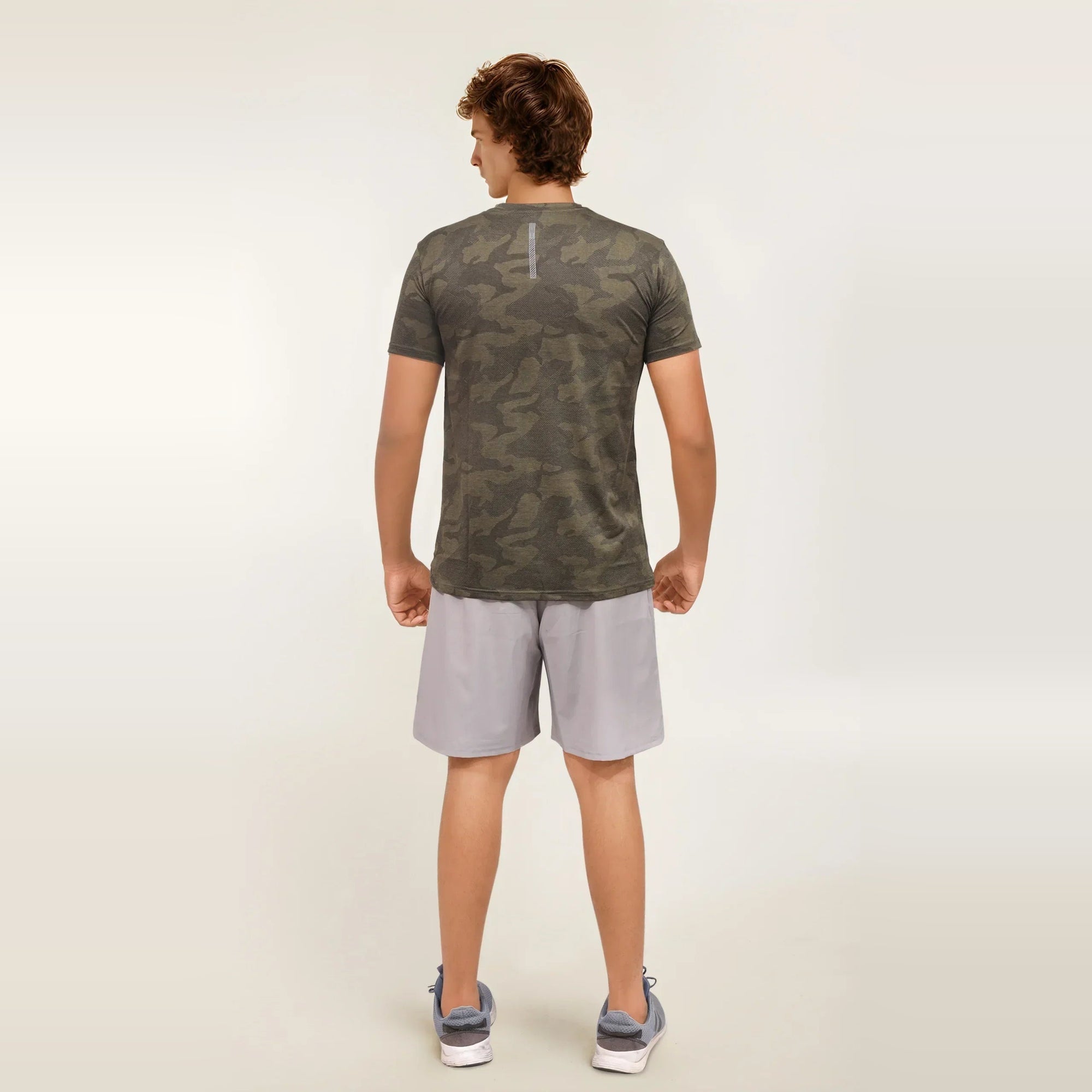 Man wearing a green camouflage, dry-fit, crew neck t-shirt from the back. Perfect for workouts.