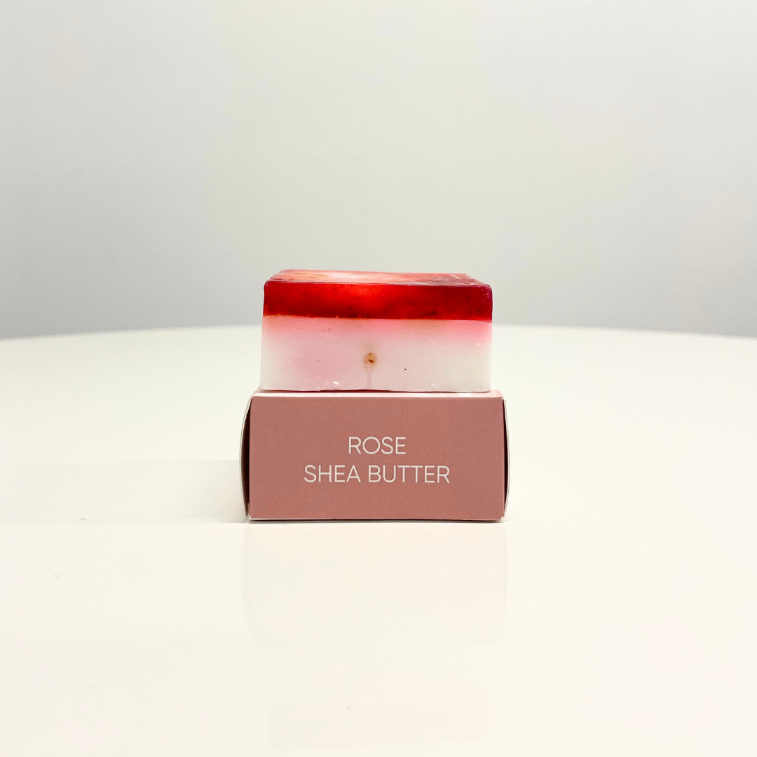 A single bar of Rose & Shea Butter Handcrafted Soap sits on its pink box.