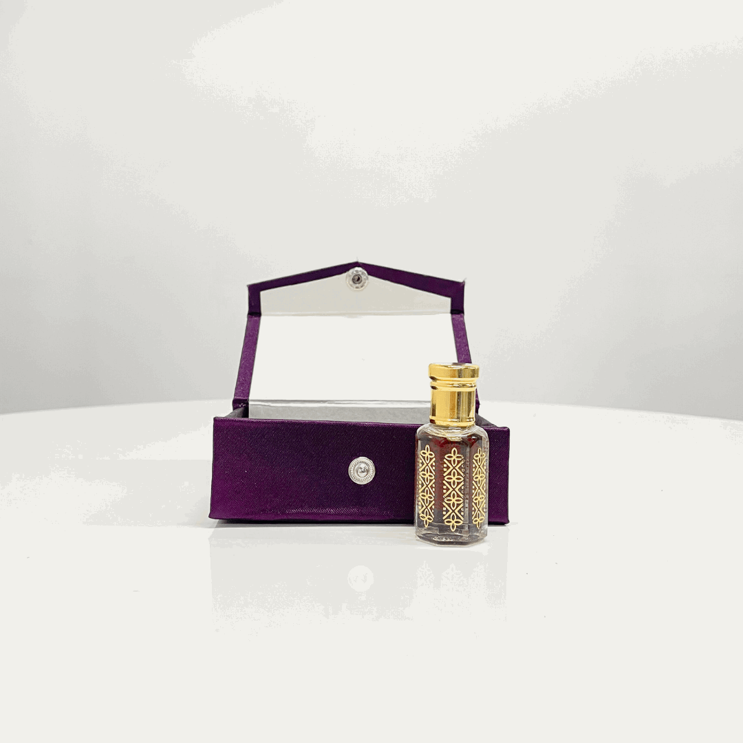 Bakhoor Attar Unisex perfume in a decorative glass bottle with a gold top, presented in an open purple velvet box.