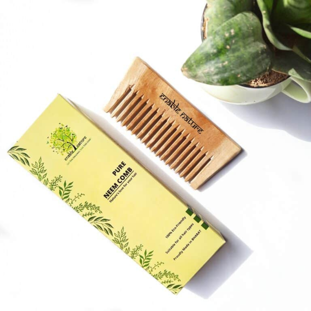 A handcrafted, wide-toothed neem wood comb lies beside its packaging. This eco-friendly detangling comb is made for all hair types.