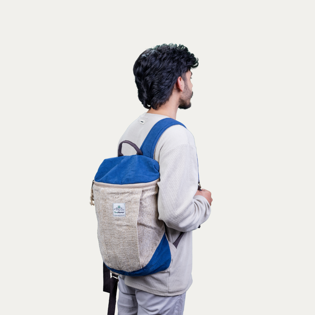 A person wears a handcrafted blue and tan hemp backpack with a pure cotton lining, showcasing its stylish design and sustainable materials.