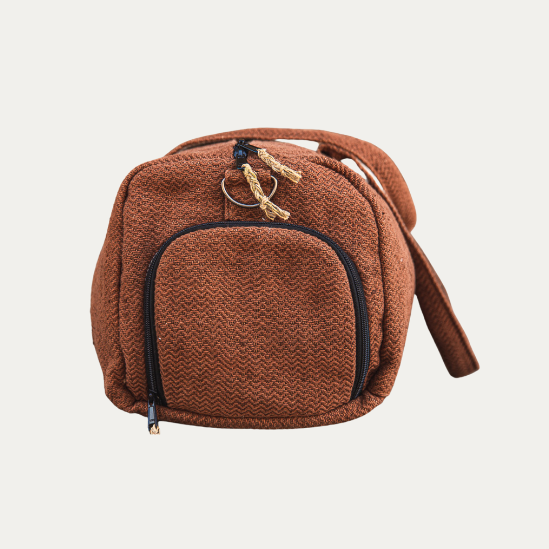 A brown Eco-friendly Hemp Duffle Bag with a separate shoe pocket, laid flat showing its side with the zipper open.