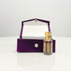 Black Oud Attar in an ornate glass bottle, nestled in a luxurious purple velvet presentation box.