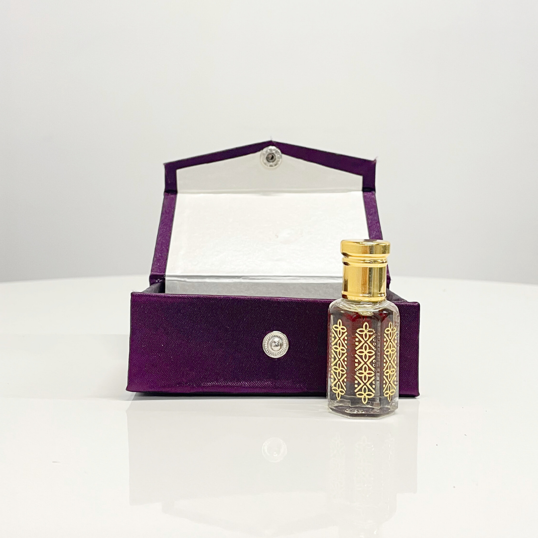 Black Oud Attar in an ornate glass bottle, nestled in a luxurious purple velvet presentation box.