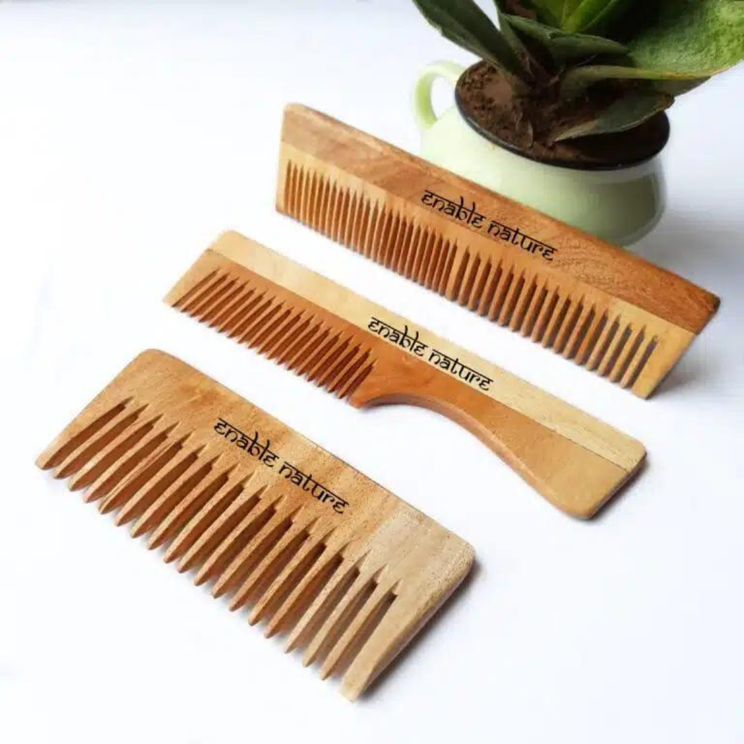 Three handmade neem wood hair combs lay on a table. This Enable Nature combo set includes combs for various hair types and needs.