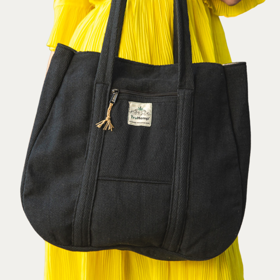 Black Himalayan hemp tote bag with zippered pocket, modeled over a yellow dress. Perfect for eco-conscious women.