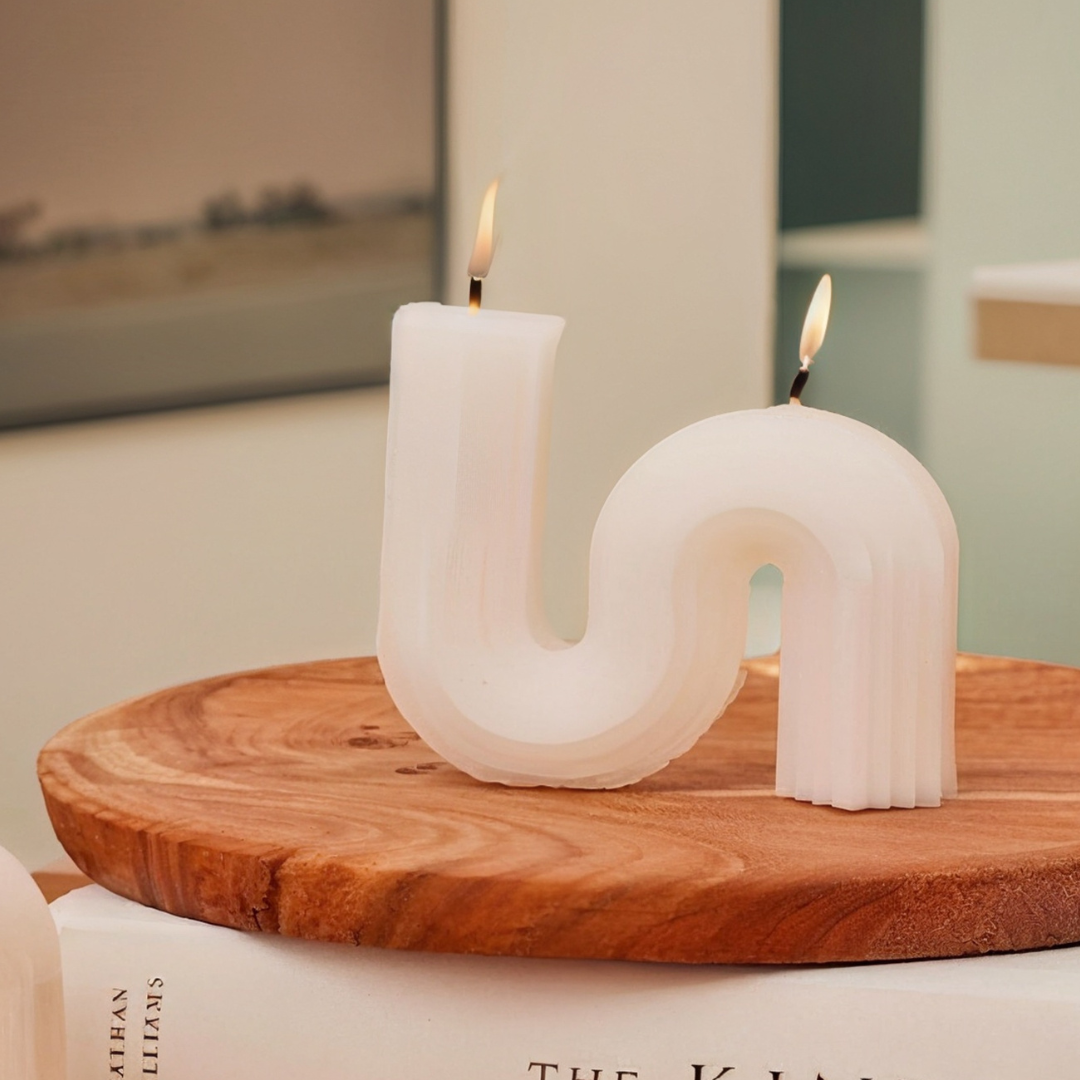 Set of 4 white soy wax candles with a unique curved, wavy design, burning brightly on a wooden tray.