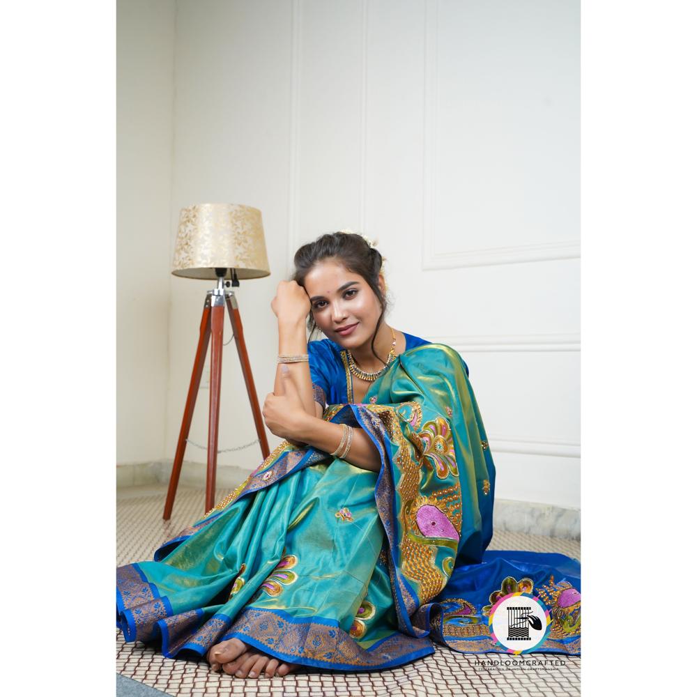 Woman in a peacock blue Banarasi tissue silk saree with intricate floral and peacock motifs, highlighting the saree's vibrant color and design.