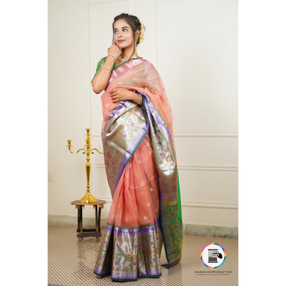 A woman gracefully wears a peach-colored "Green Peach Printed Soft Banarasi Tissue Silk Saree", showcasing its intricate floral print and silver border.