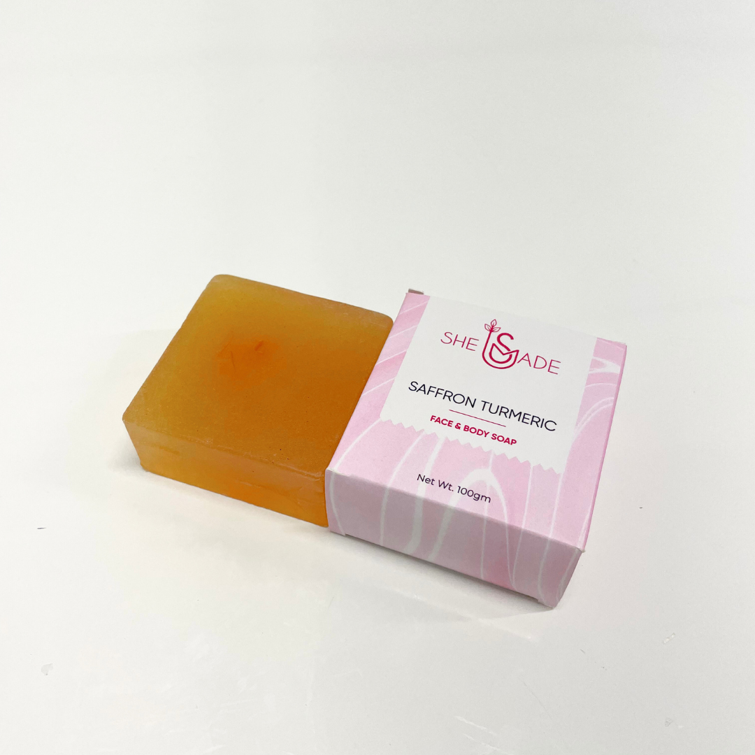 A bar of golden-hued Saffron Turmeric Handcrafted Soap next to its pink branded box, ideal for face and body.