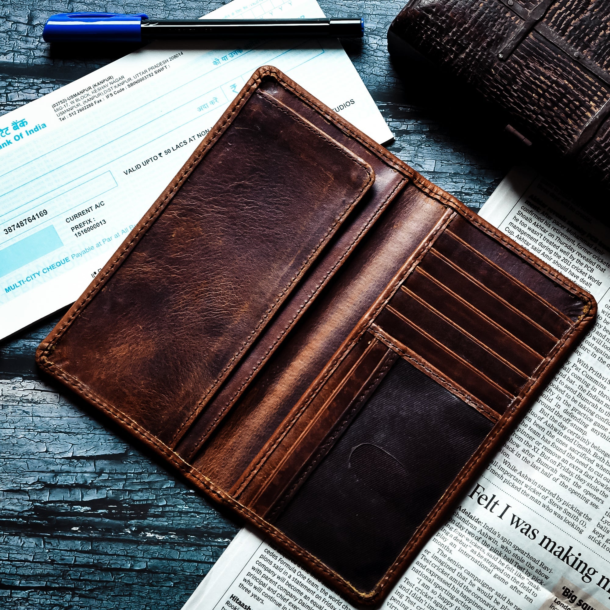 Open brown leather bifold men's wallet with multiple credit card slots, cash compartments, and an ID window.