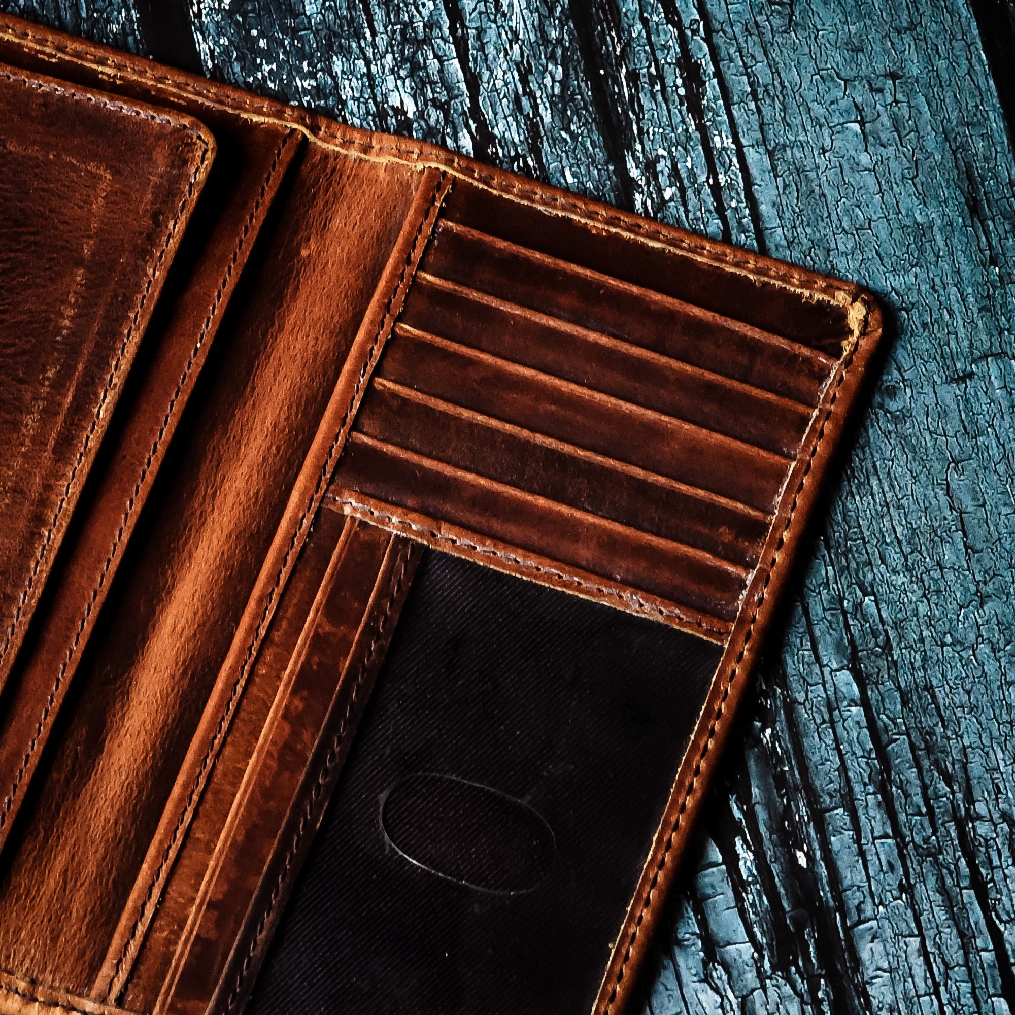 Open brown leather bifold wallet showing multiple credit card slots and ID window.