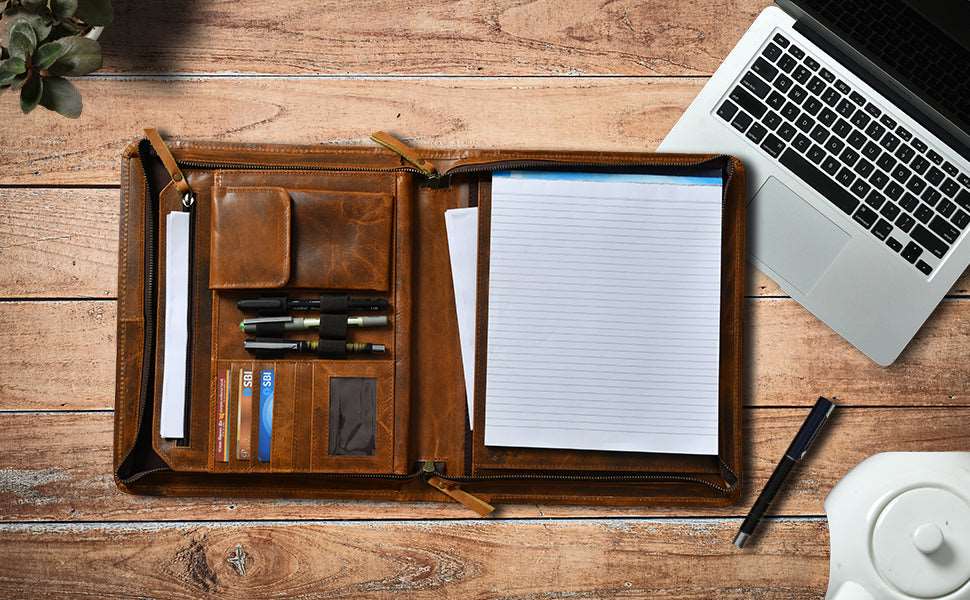 Open cognac leather padfolio organizer with notepad, pen slots, pockets, and large inside compartment for a laptop or tablet.