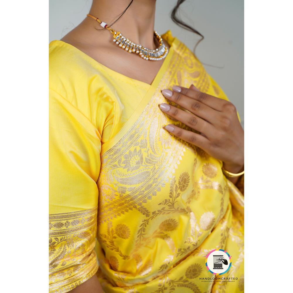 Woman wearing a vibrant Sunflower Yellow Banarasi Tissue Silk Saree with intricate silver floral designs.