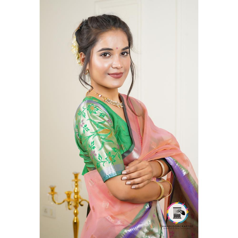 Woman wearing a green and peach Banarasi tissue silk saree with floral print, showcasing its elegant drape and vibrant colors.