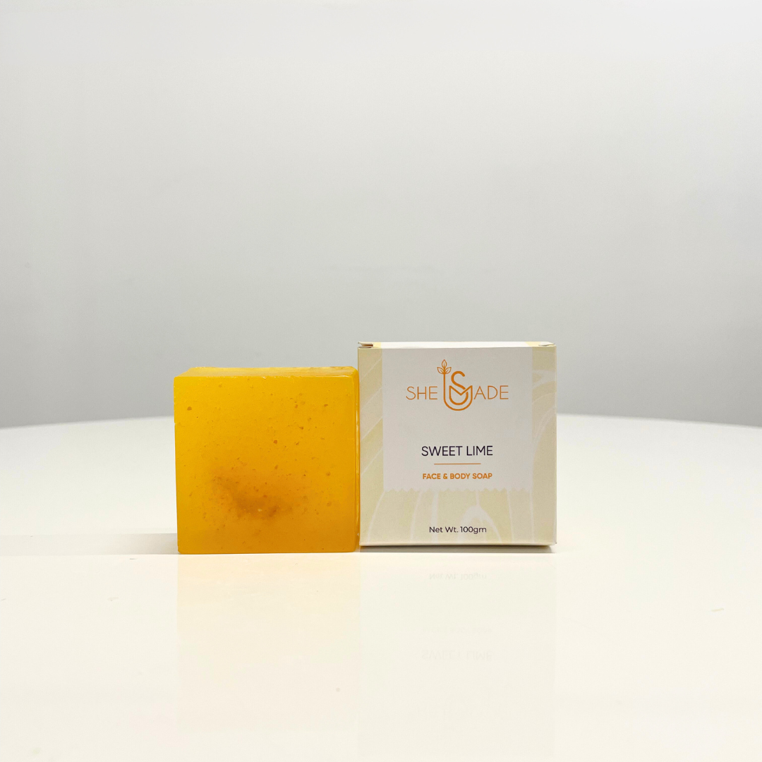 A bright yellow, handcrafted Sweet Lime soap by She Made sits next to its box, ready to provide a refreshing face and body cleanse.