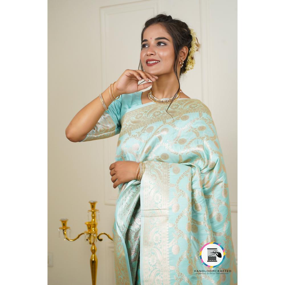 Woman wearing a sky blue Banarasi tissue silk saree with intricate gold print, showcasing its elegance and drape.