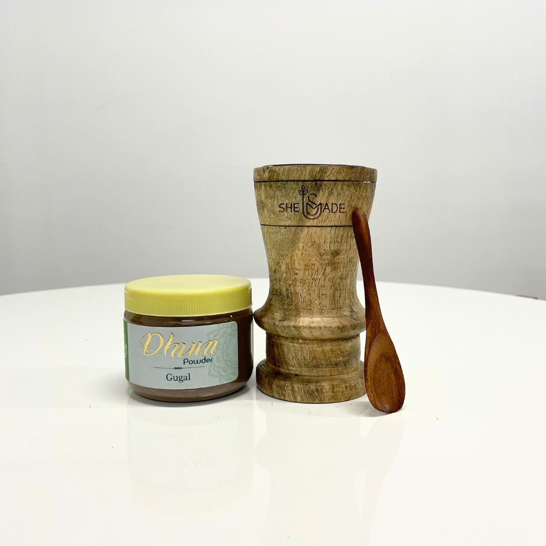 A jar of Gugal Dhuni Powder (Bakhoor) sits next to a wooden incense burner and small spoon, ready to fill your home with a rich, aromatic fragrance.