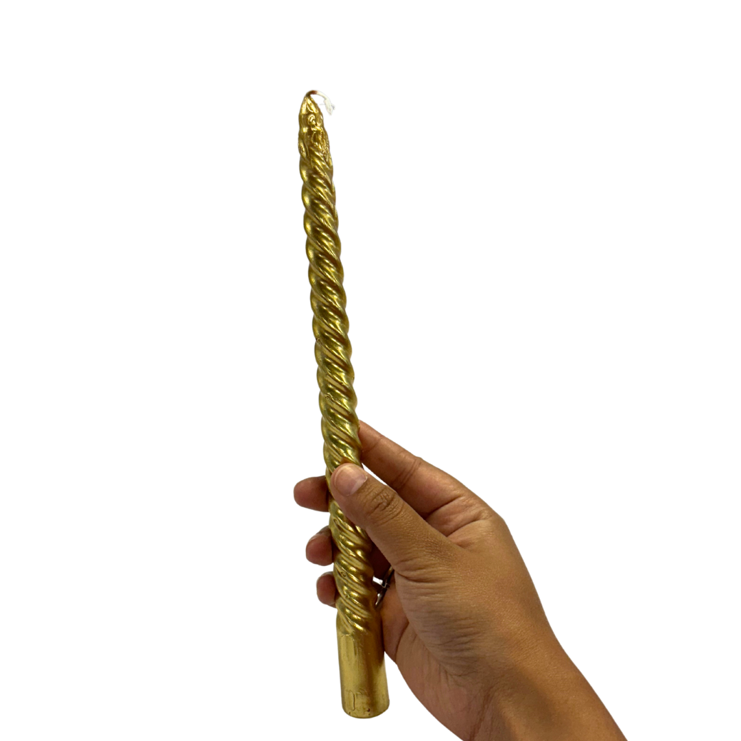 A hand holds a long, twisted gold dripless and smokeless taper candle, showcasing its elegant design.